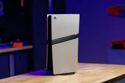 En vit PlayStation 5 står vertikalt på ett träbord.