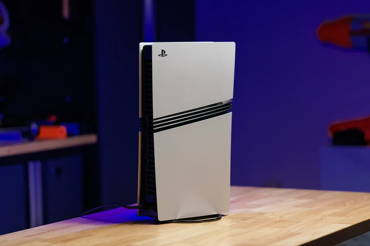 En vit PlayStation 5 står vertikalt på ett träbord.