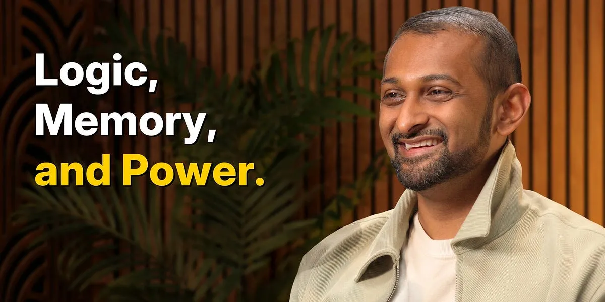 En man med kort, mörkt hår och skägg ler mot kameran. I bakgrunden texten "Logic, Memory, and Power.