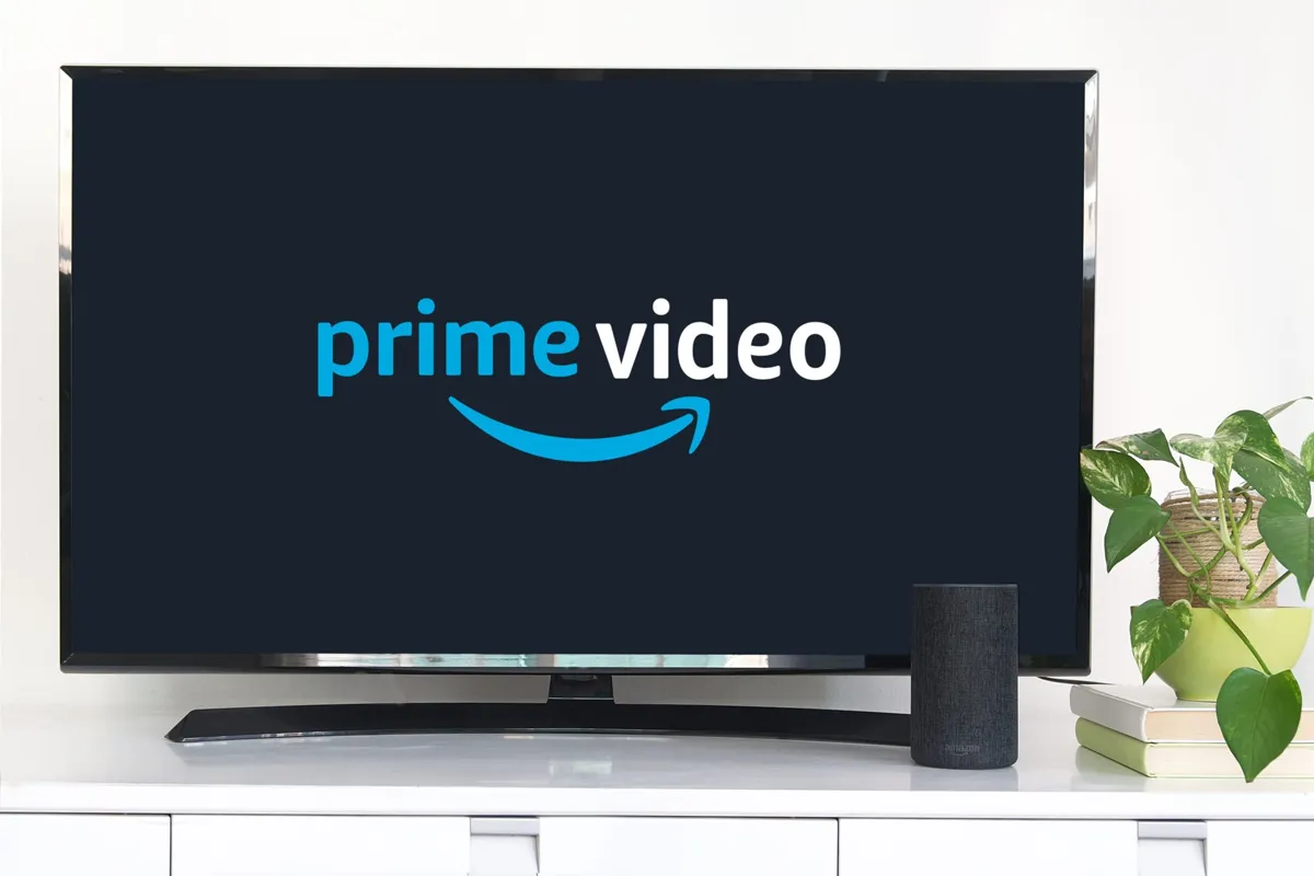 En TV visar Prime Videos logotyp. En Amazon Echo står bredvid. En växt och böcker syns också.