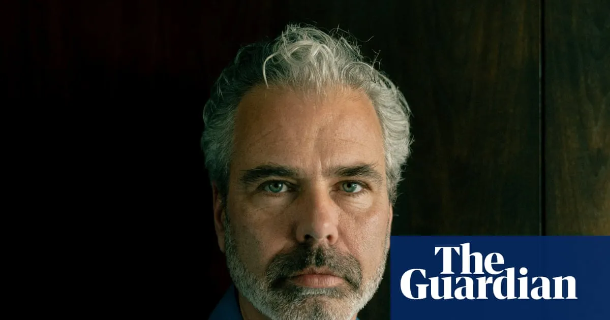 Närbild på man med grått hår och skägg, mot mörk bakgrund. Logotypen "The Guardian" syns i nedre högra hörnet.