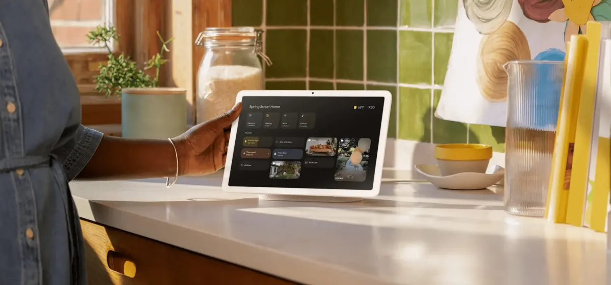 En person använder en Google Nest Hub-skärm på en köksbänk. Skärmen visar en hemautomatiseringspanel.