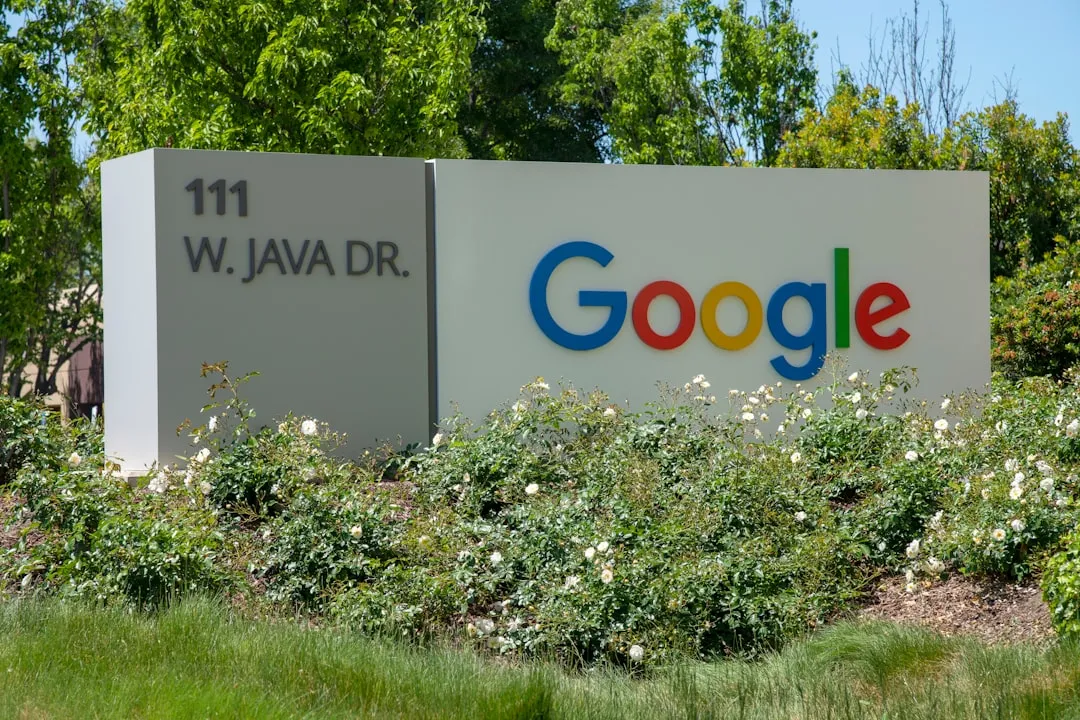 En skylt med texten "111 W. JAVA DR." och Google-logotypen, omgiven av grönska.