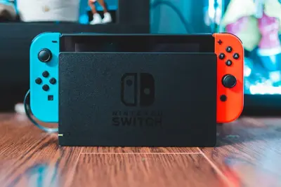 En Nintendo Switch-konsol i dockningsstationen på ett träbord.