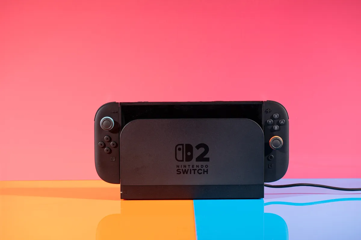 En svart Nintendo Switch 2 i dockningsstation mot en rosa bakgrund.