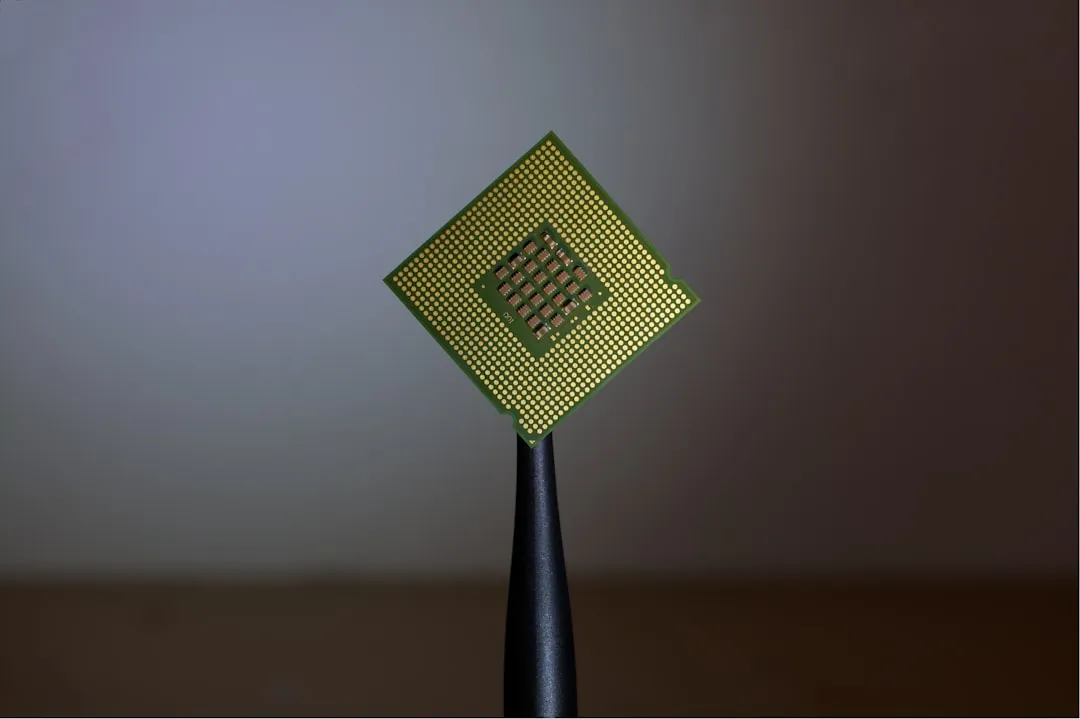 En processor hålls upp av en pincett mot en grå bakgrund.