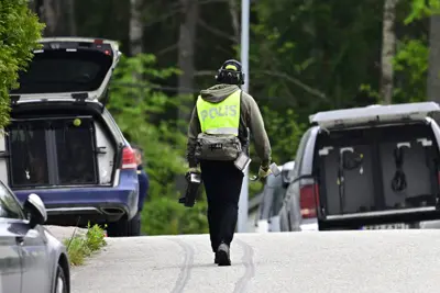 En polis i gul väst går mot två bilar med öppna bakluckor.