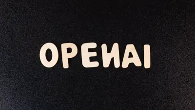 Texten "OPENAI" skriven med ljusa träbokstäver mot en svart bakgrund.