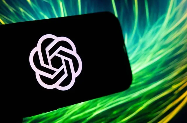 En mobiltelefon visar ChatGPTs logotyp mot en grön och gul bakgrund.