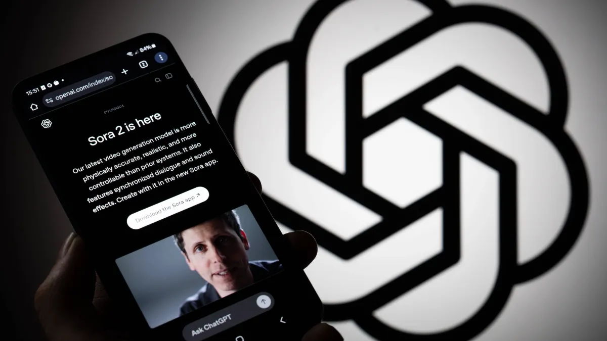 En mobiltelefon visar OpenAIs webbsida om Sora 2. I bakgrunden syns OpenAIs logotyp.