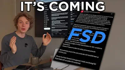 En man sitter vid ett skrivbord med en dator och en mugg. Bakom honom syns en skärm med texten "IT'S COMING" och en tweet om Teslas självkörande mjukvara.