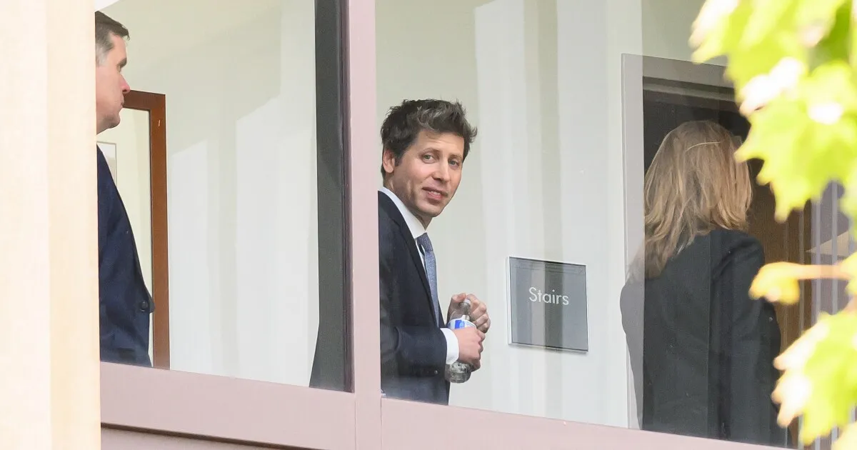 En man i kostym syns genom ett fönster, hållandes en vattenflaska. En skylt med "Stairs" syns också.